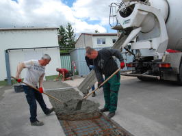 Mitarbeiter der Bauabteilng beim verfüllen des Loches im Betonweg.