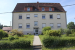 Großes Wohnhaus mit zahlreichen Fenstern und einem gepflegten Garten, Ansicht von der Vorderseite.