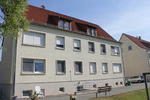Rückansicht eines großen Wohnblocks, der Mietwohnungen zeigt, eingebettet in eine grüne Umgebung.